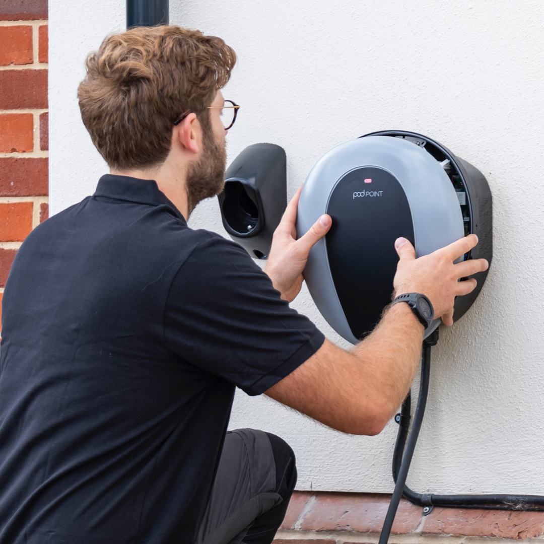 Man installing a round wall-mounted electric vehicle charging point.