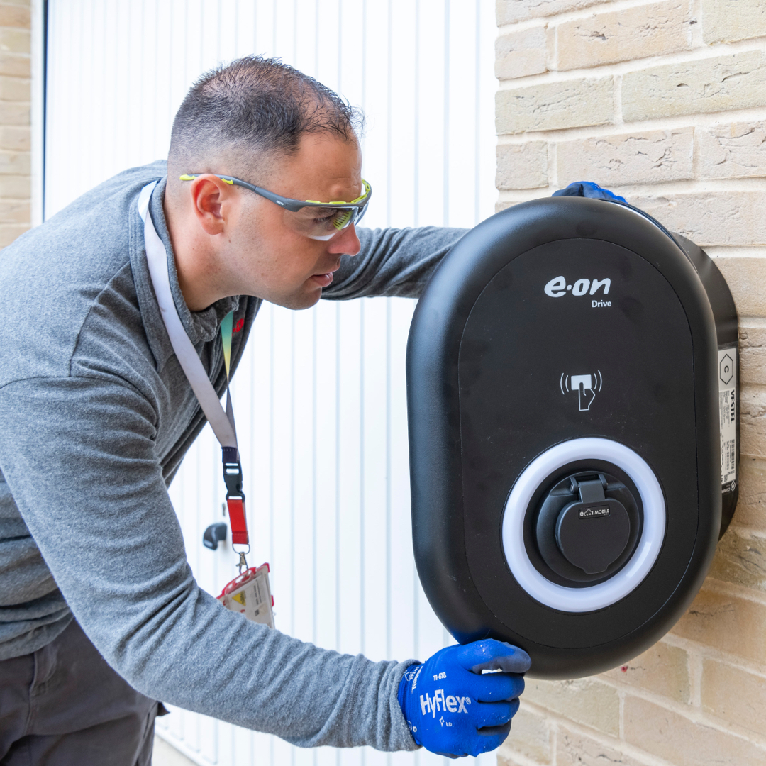 Man inspecting an electric vehicle charging device on a wall.