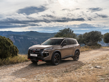 SUV parked on a rural dirt road with hills and cloudy sky in the background.