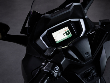 Close-up of a motorcycle dashboard with digital display and controls.