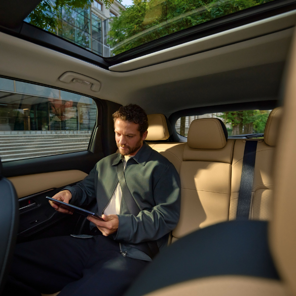 Man sitting in a car's back seat, using a tablet.