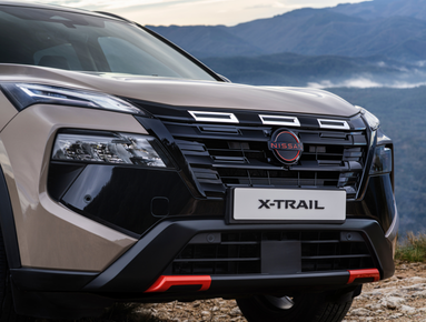 Close-up of a Nissan X-Trail SUV front view with logo and grille.