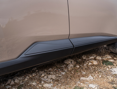 Close-up of car's side panel and door on a rocky surface.