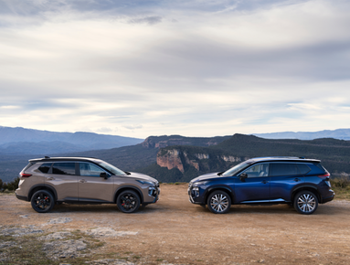 Two SUVs parked facing each other on a dirt path with mountains in the background.