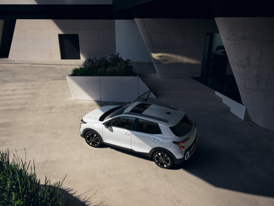 Aerial view of a parked white SUV with open driver's door next to a modern building.