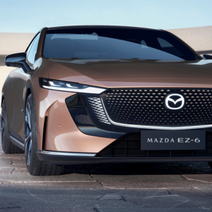 Front view of a bronze Mazda EZ-6 car with a detailed grille and sleek headlights.