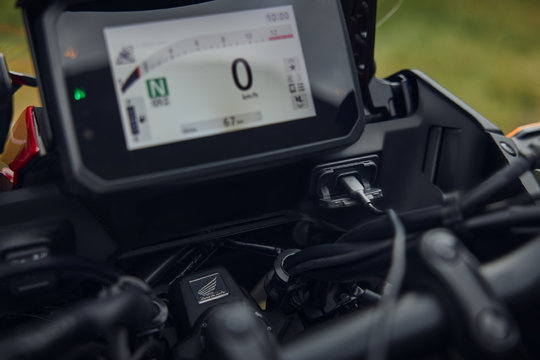 Close-up of a motorcycle's digital dashboard and USB ports.