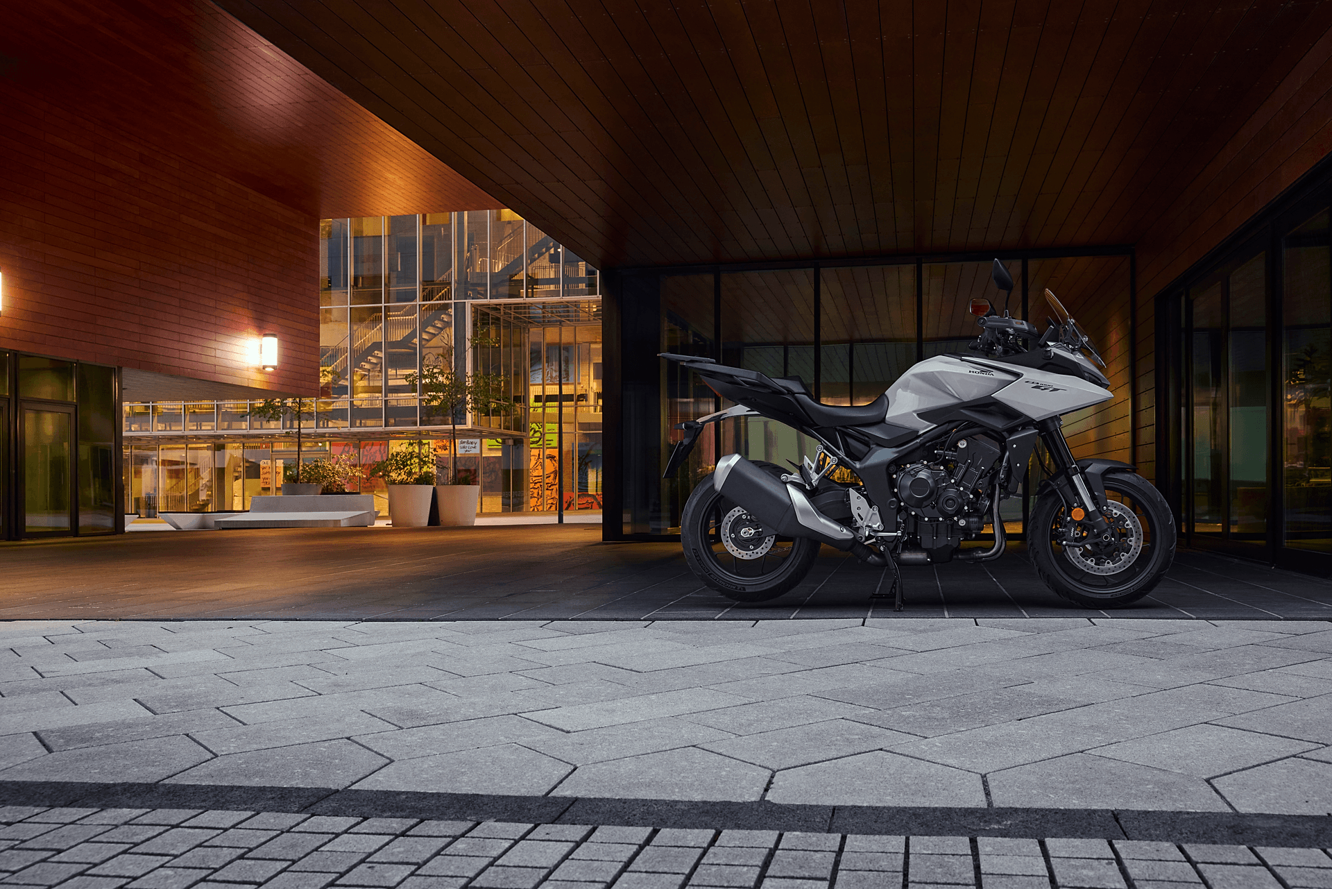 Silver motorcycle parked under a modern wooden ceiling structure.
