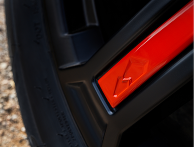 Close-up of a red accent on a black alloy wheel with a tyre visible on the left.