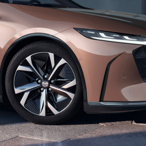 Close-up of a parked car's front left wheel and headlight, showing the vehicle's sleek design.
