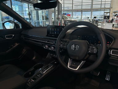 Interior of a car showing the steering wheel, dashboard, and touchscreen display.