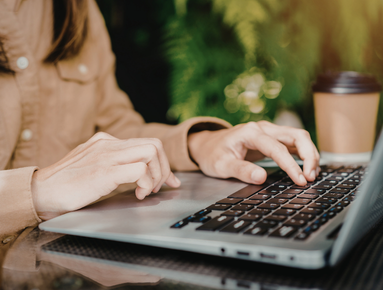 Person typing on a laptop with a coffee cup nearby.