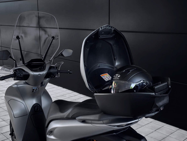 Scooter with open top box containing a helmet.
