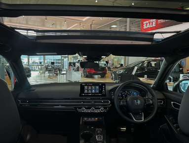 Interior view of a car dashboard and steering wheel in a showroom setting.