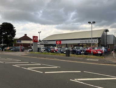 Nissan car dealership with signage and parked cars on display.