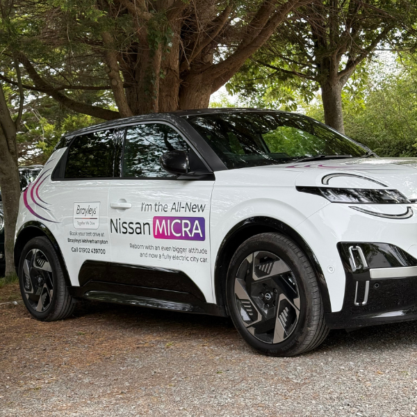 White Nissan Micra electric vehicle with promotional text on the side.