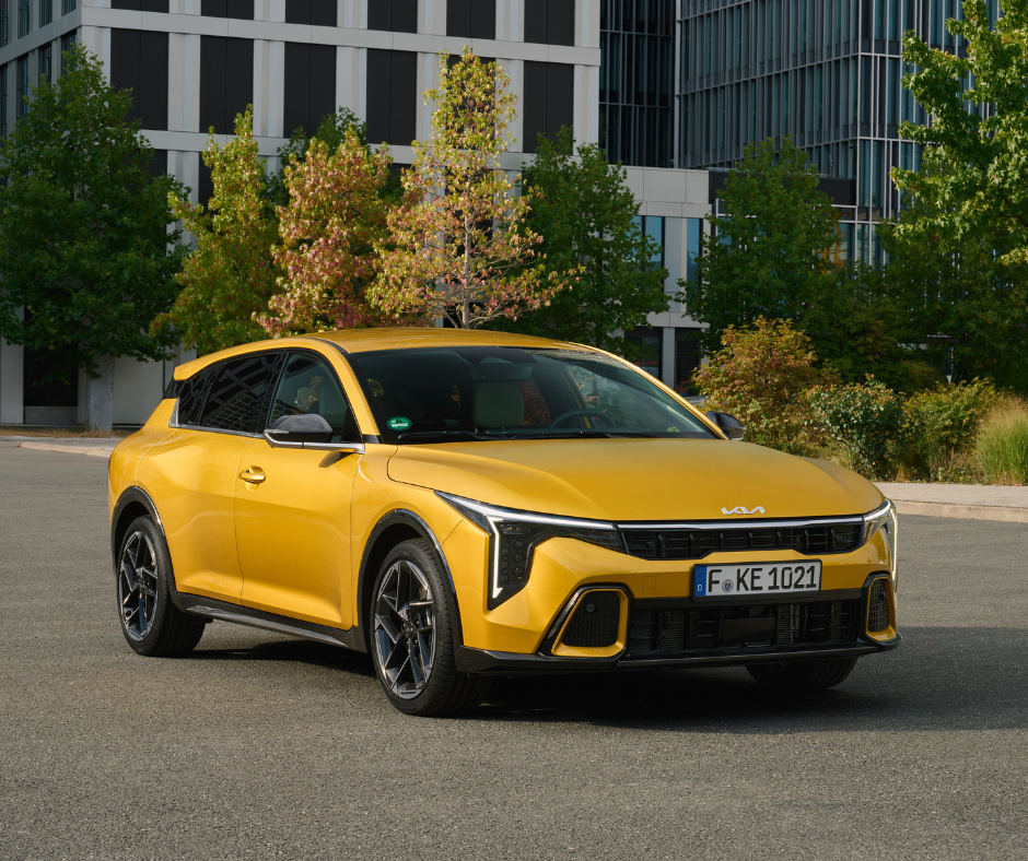 Yellow car parked in front of modern buildings and trees.