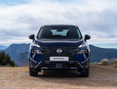 Front view of a dark blue Nissan X-Trail SUV parked on a dirt road.