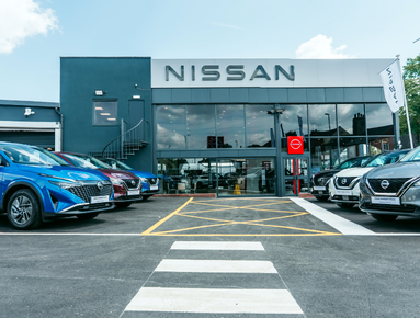 Nissan car dealership with various cars parked outside.