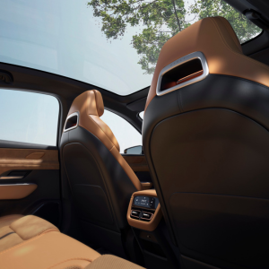 Car interior with brown leather seats, panoramic sunroof, and digital rear console.