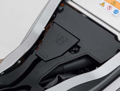 Close-up of a vehicle component with caution labels and visible wiring.