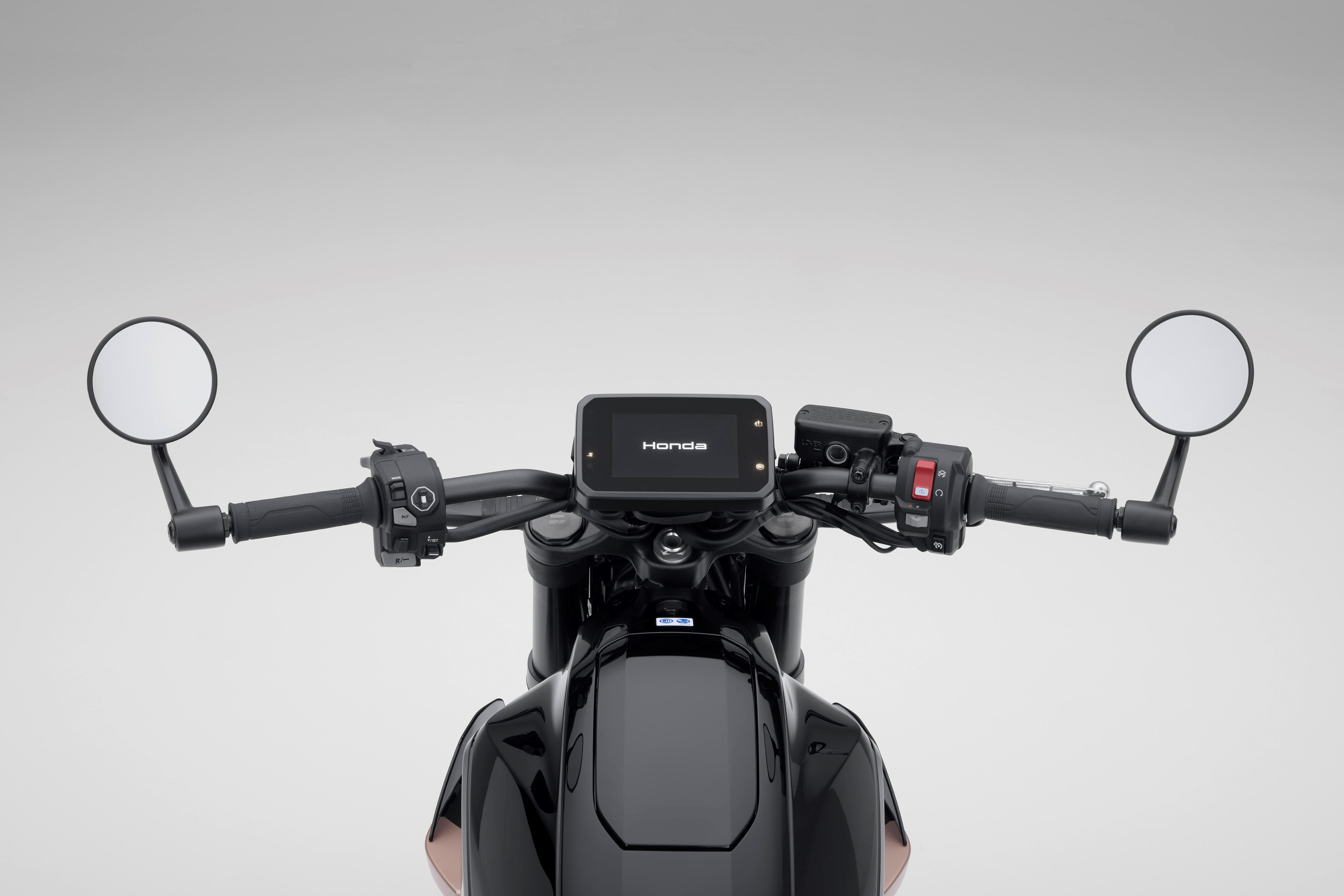 Motorcycle handlebars with mirrors and a digital dashboard displaying the Honda logo.