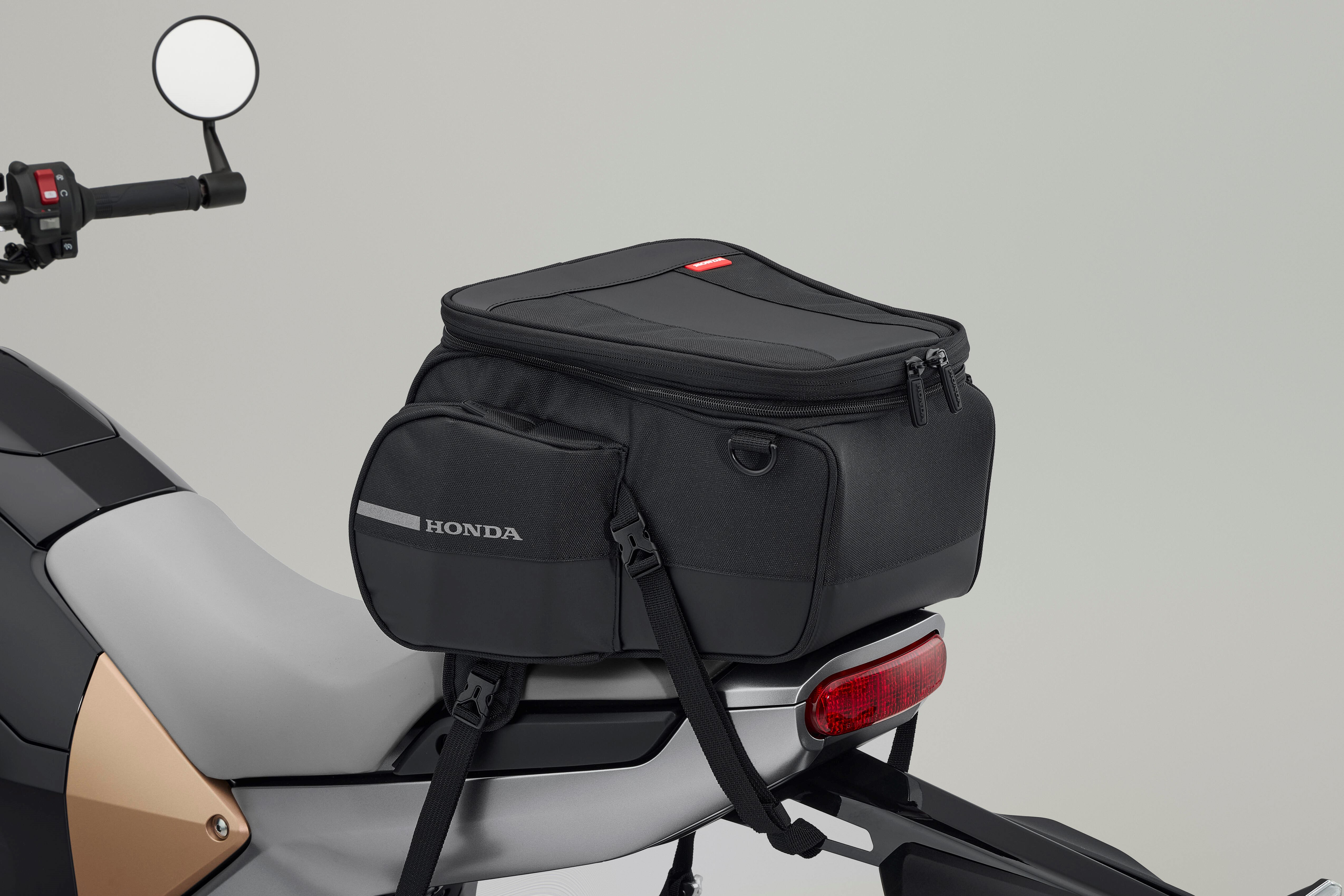 Black Honda motorcycle bag secured on bike seat with straps.