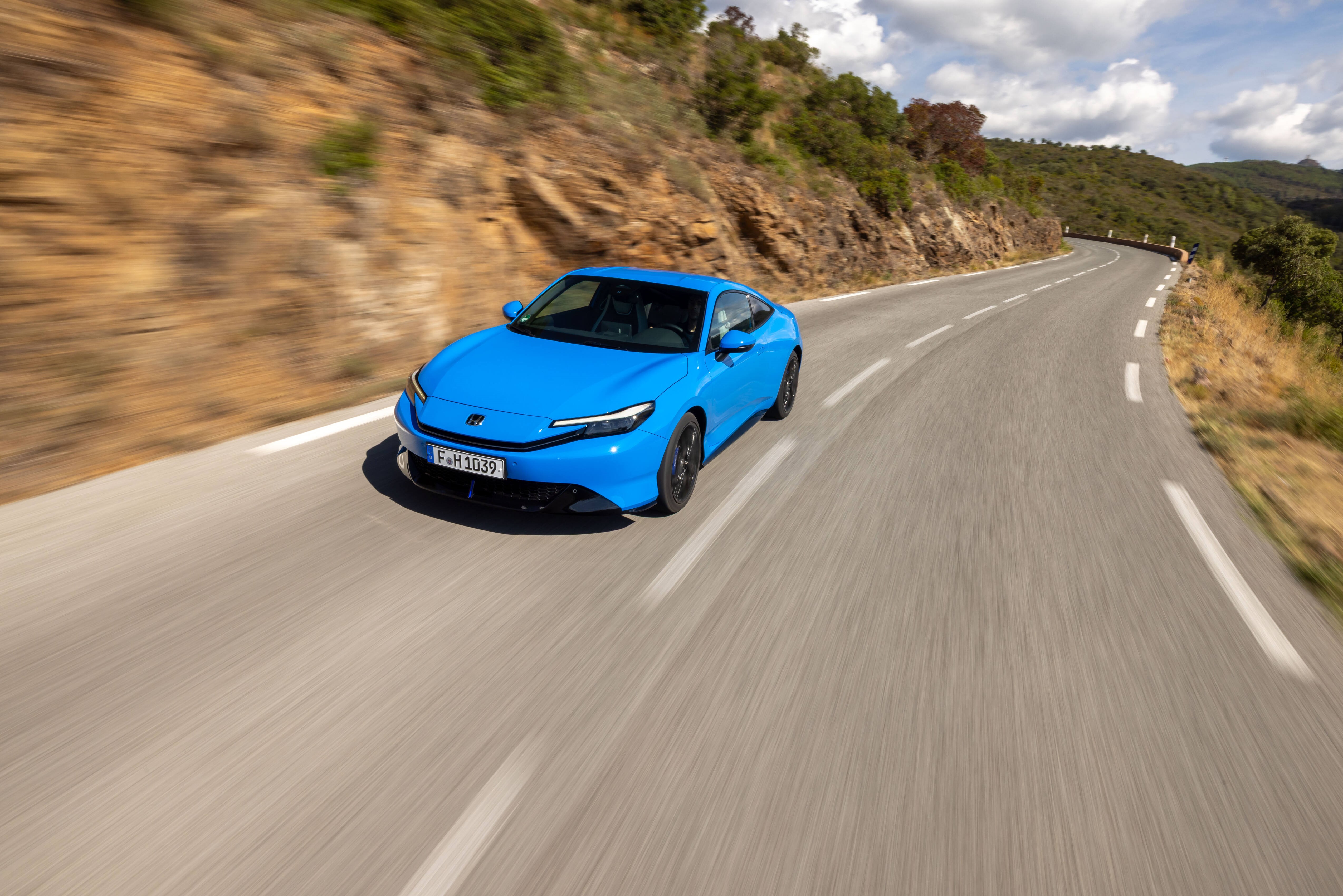 Blue sports car driving on a winding road.