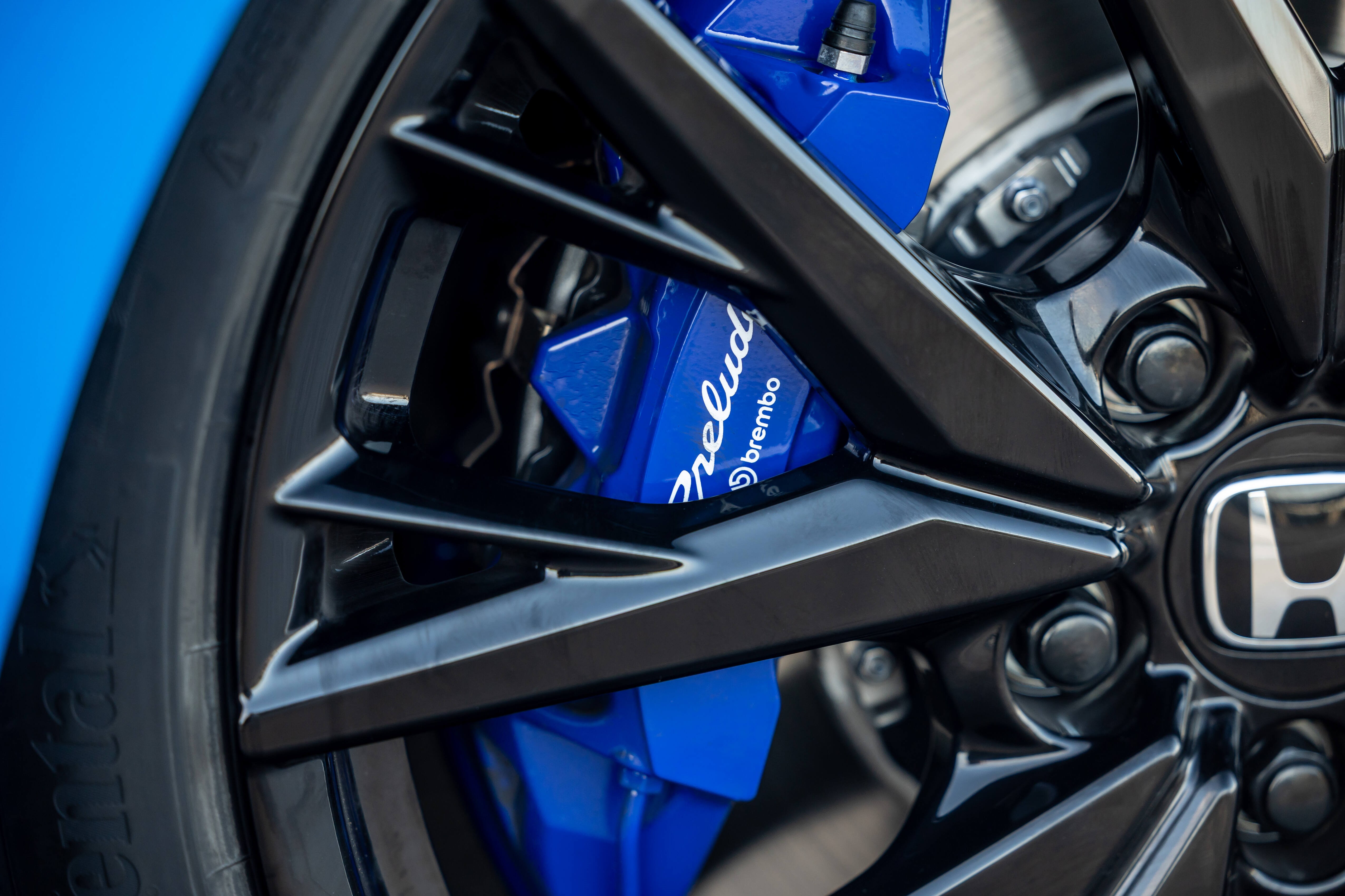 Close-up of a black car wheel with a blue Brembo brake caliper.