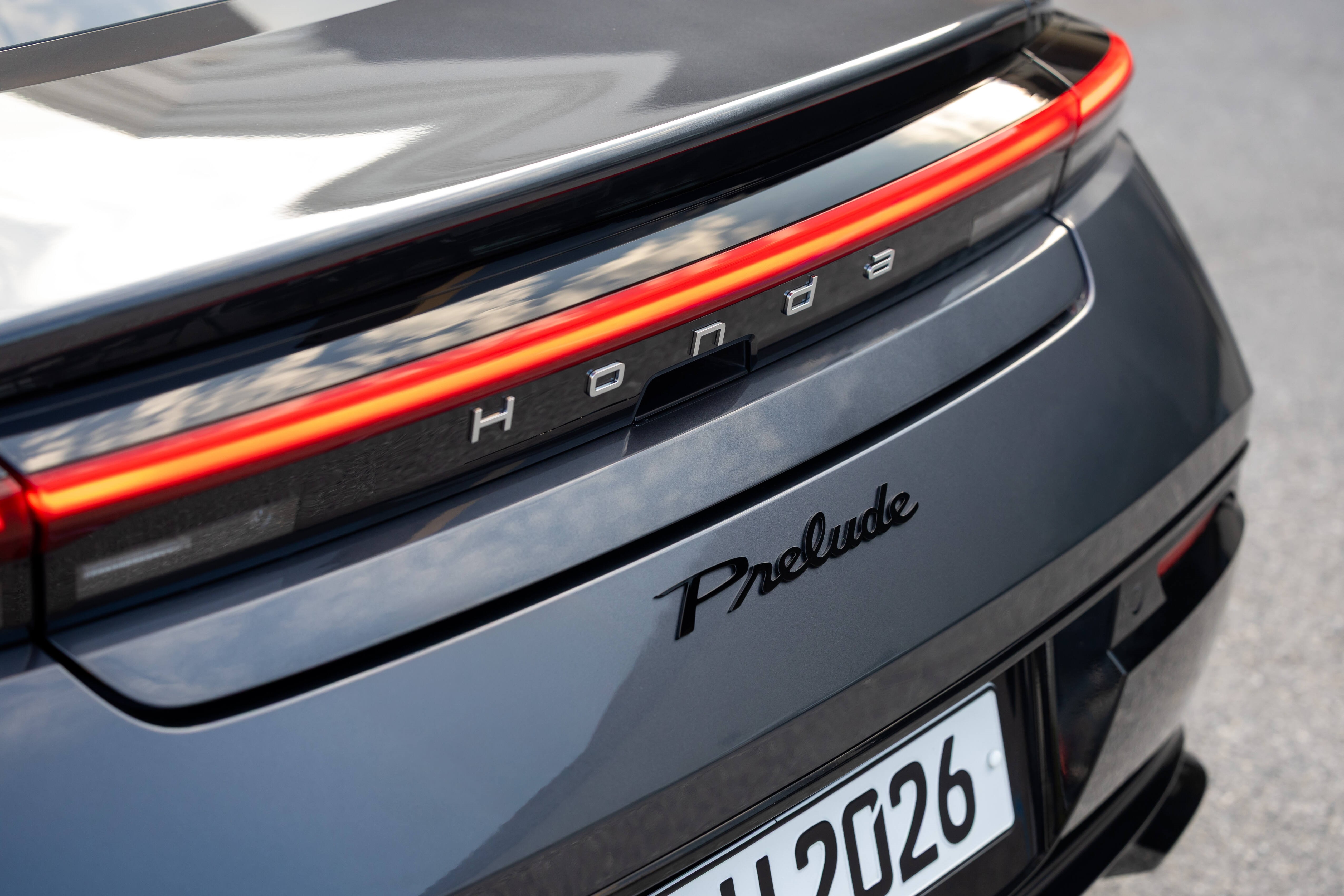 Close-up of Honda Prelude logo and number plate on car rear.