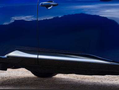 Side view of a blue car door and handle with a reflective surface near the ground.