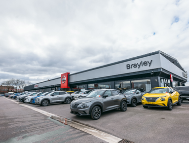 Car dealership forecourt with various vehicles on display.
