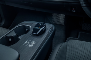 Centre console of a car interior with gear selector and cup holders.