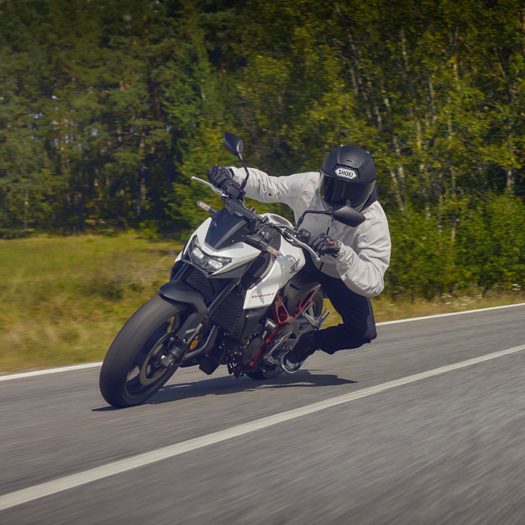 Rider leaning into a turn on a white motorbike on a road.