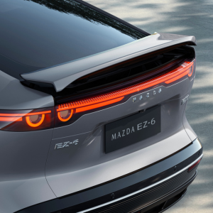 Rear view of a grey Mazda EZ-6 car with illuminated tail lights.