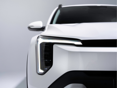 Close-up of a white car's front headlight and part of the bonnet.