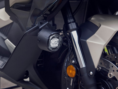 Close-up of a motorcycle front fork with a spotlight and visible brake disc.