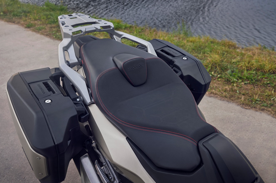 Motorbike seat and luggage boxes beside a body of water.