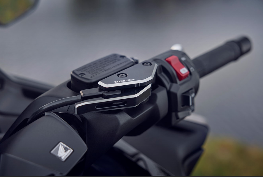 Close-up of a motorcycle handlebar with brake lever, cables, and control switches.