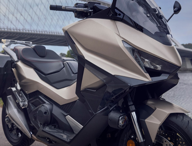 Modern matte grey motorcycle parked near a bridge.