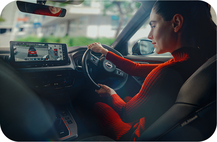 Woman in red top driving a car, focusing on the road, with navigation screen visible.