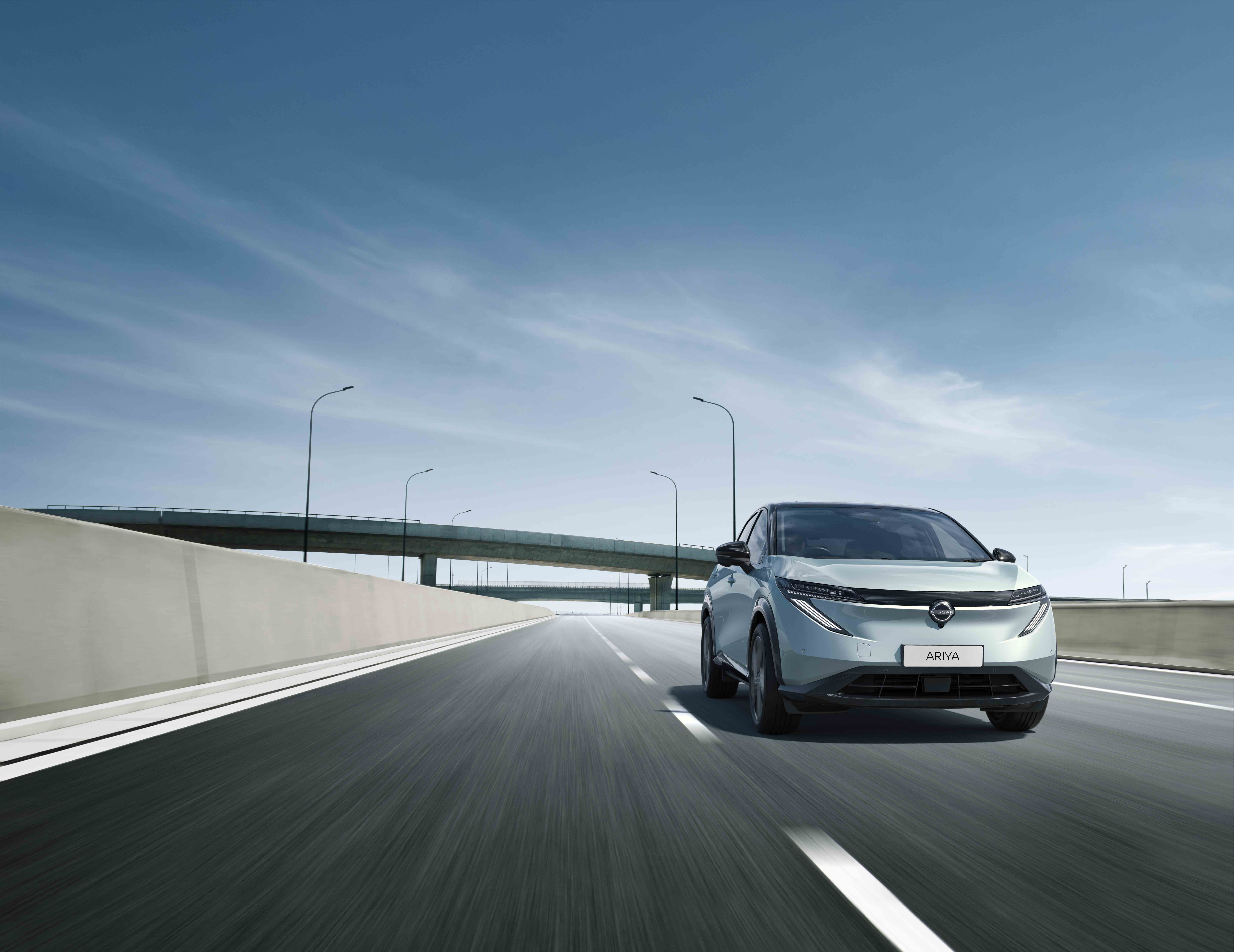 Silver car driving on a motorway under a blue sky.