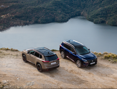 Two SUVs parked on a hilltop overlooking a lake.