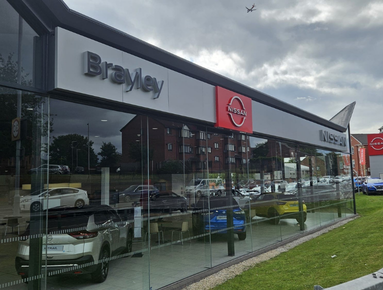 Exterior of a Nissan car showroom with cars visible through glass windows.