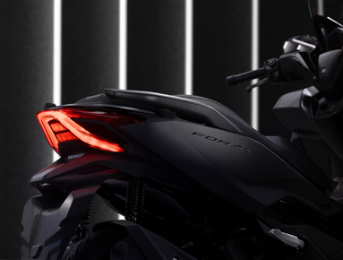 Close-up of a motorbike's rear with illuminated tail light and visible Forza branding.