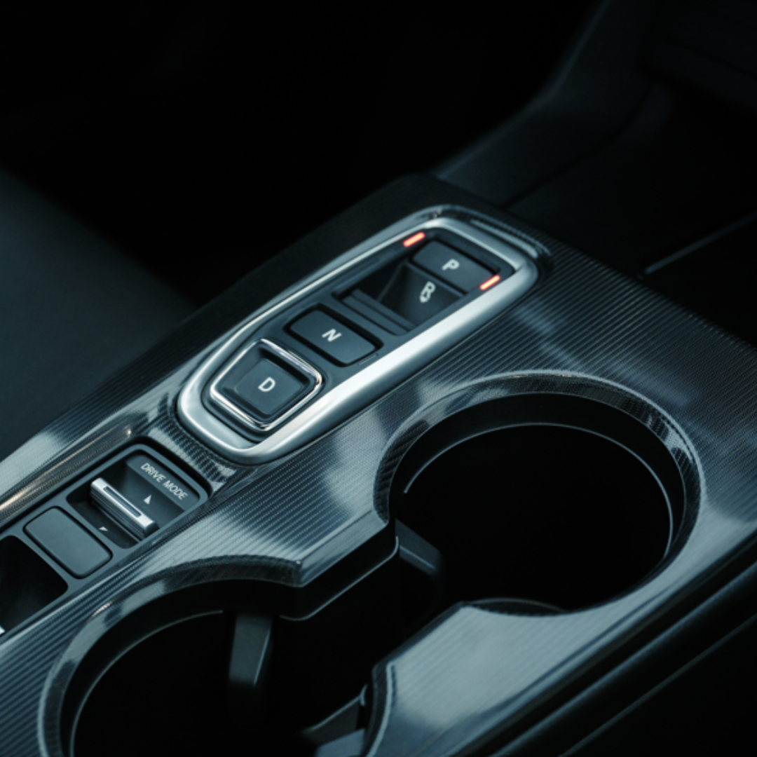 Close-up of a car centre console with gear shift buttons and cup holders.