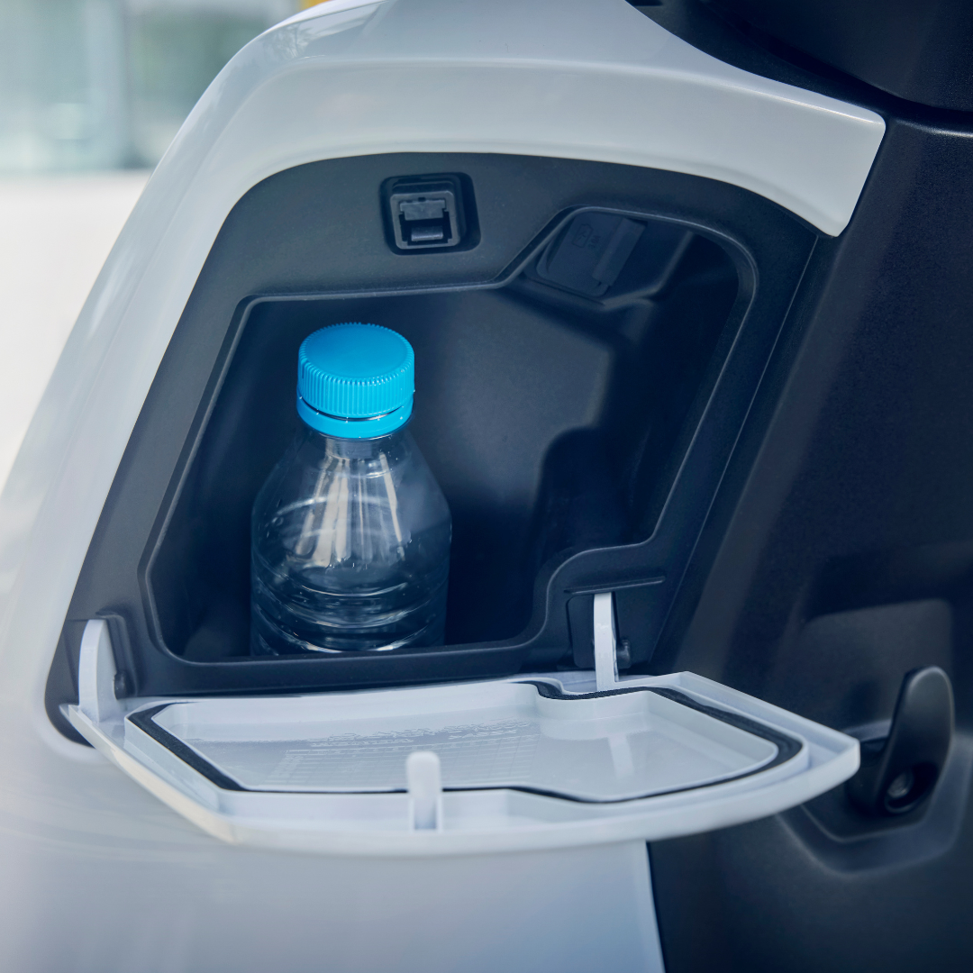 A plastic bottle with a blue cap stored in a vehicle's compartment.