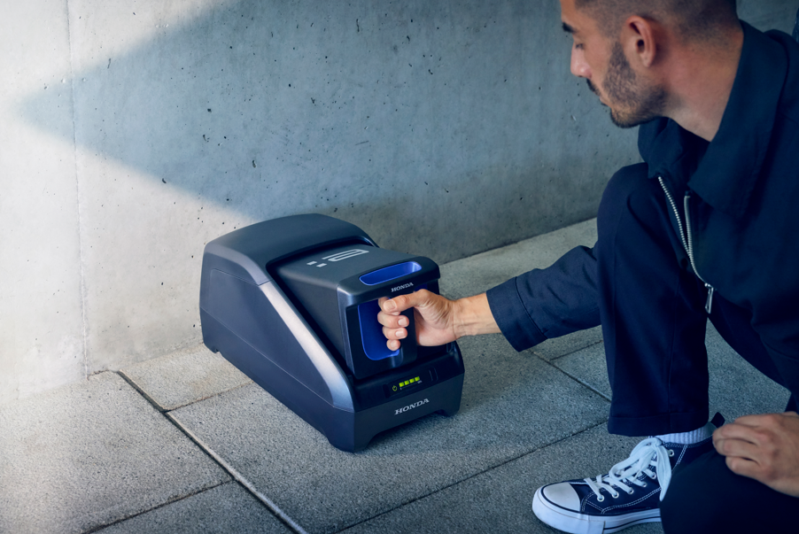 Man interacting with a Honda device on the ground.