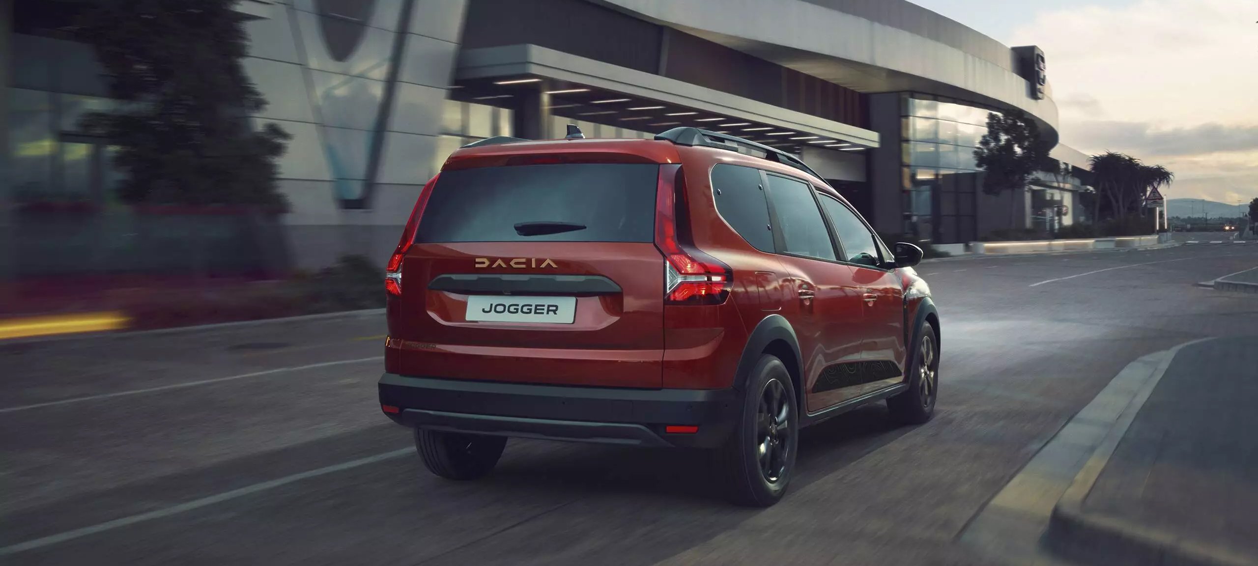 Red Dacia Jogger car in motion on road.