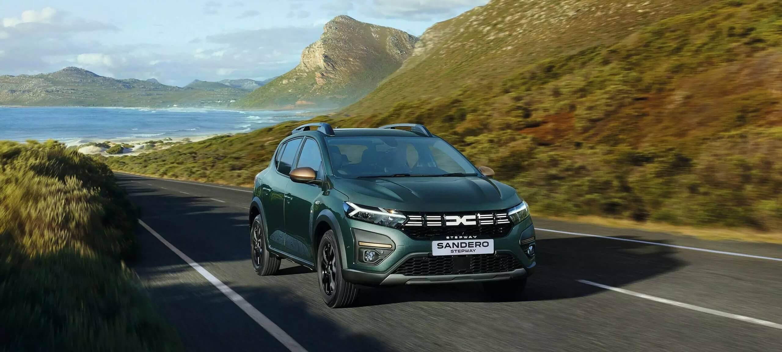 Green Dacia Sandero driving on coastal road.